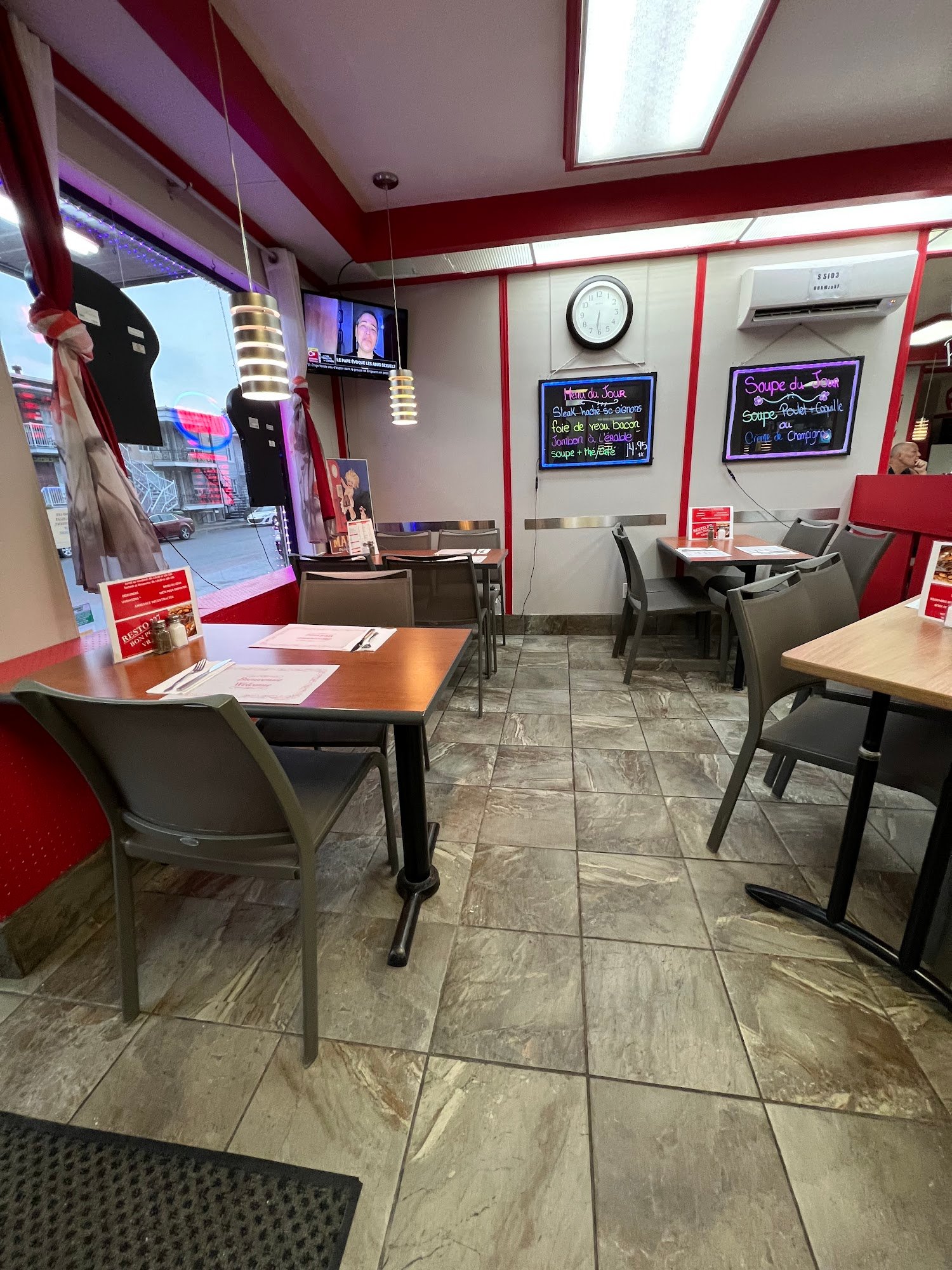 La salle à manger du restaurant, avec ses tables de quartier et ses accents rouges
